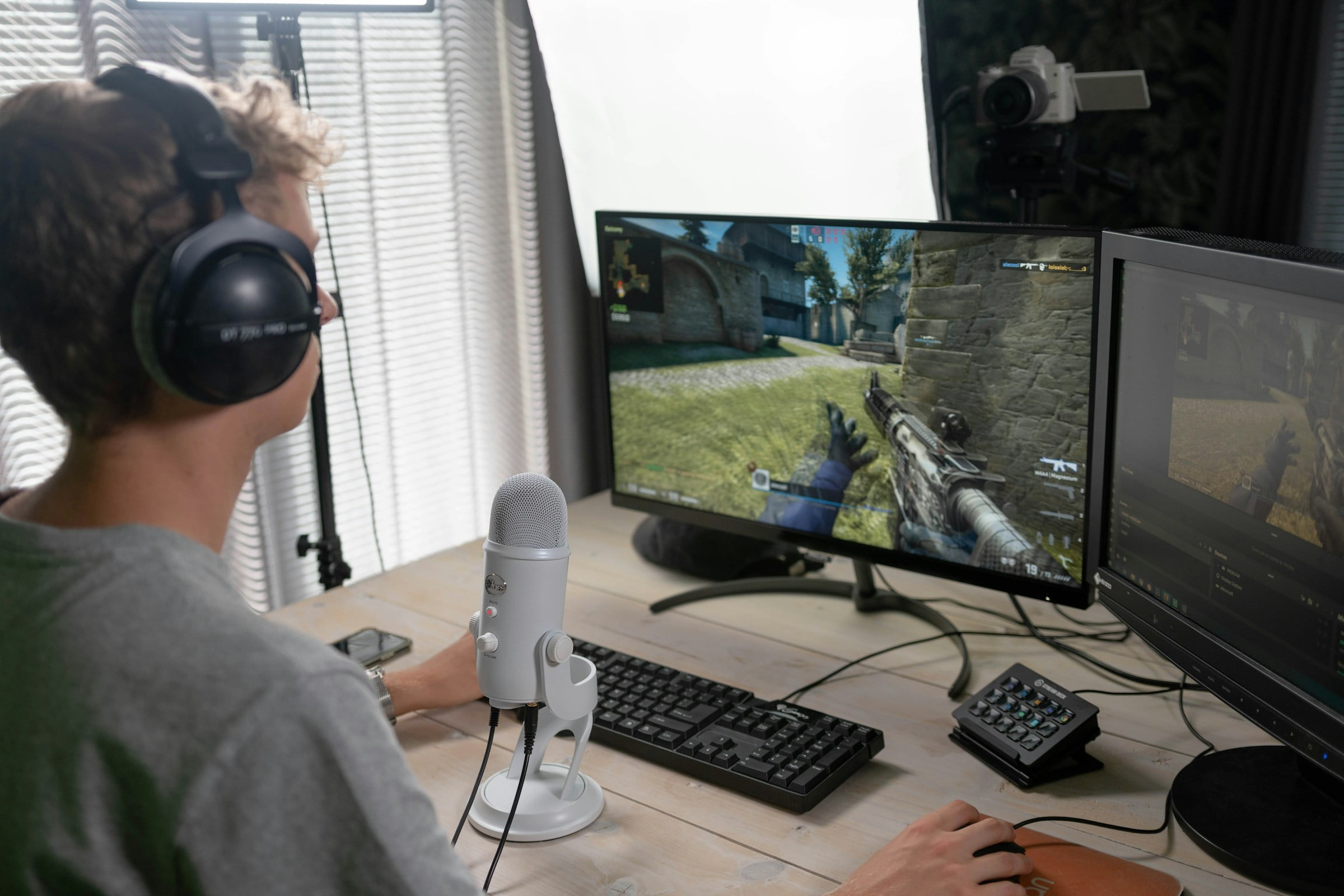 Usuario haciendo streaming de un videojuego con un micrófono y una cámara DSLR
