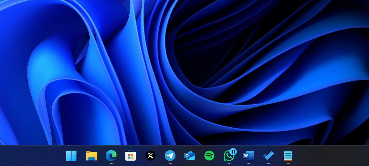 Imagen que muestra la barra de tareas de Windows 11 con numerosos iconos anclados y sobre un fondo oscuro.