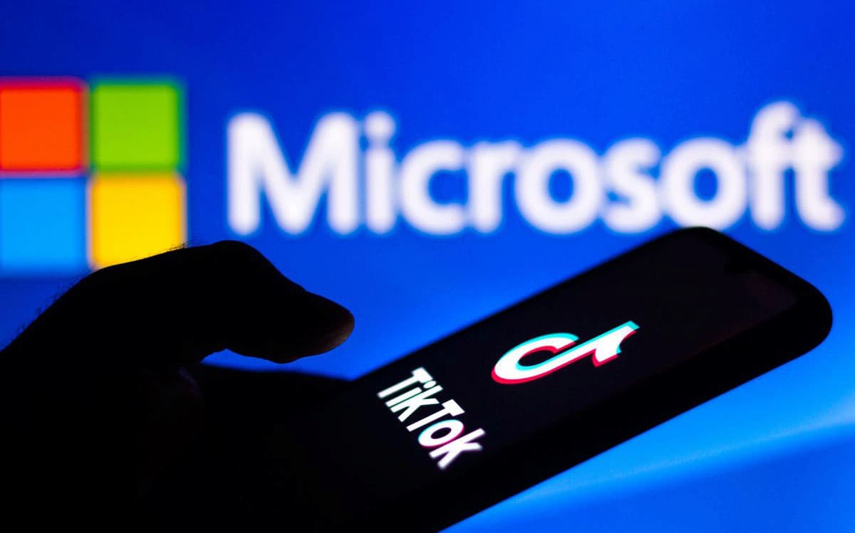 Imagen de un móvil con TikTok y el logo de Microsoft de fondo