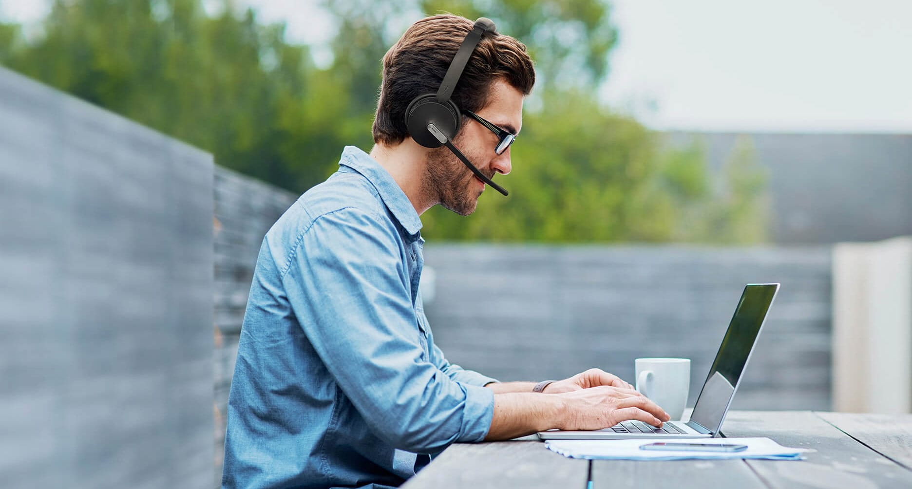 Imagen de una persona usando el portátil con cascos Bluetooth